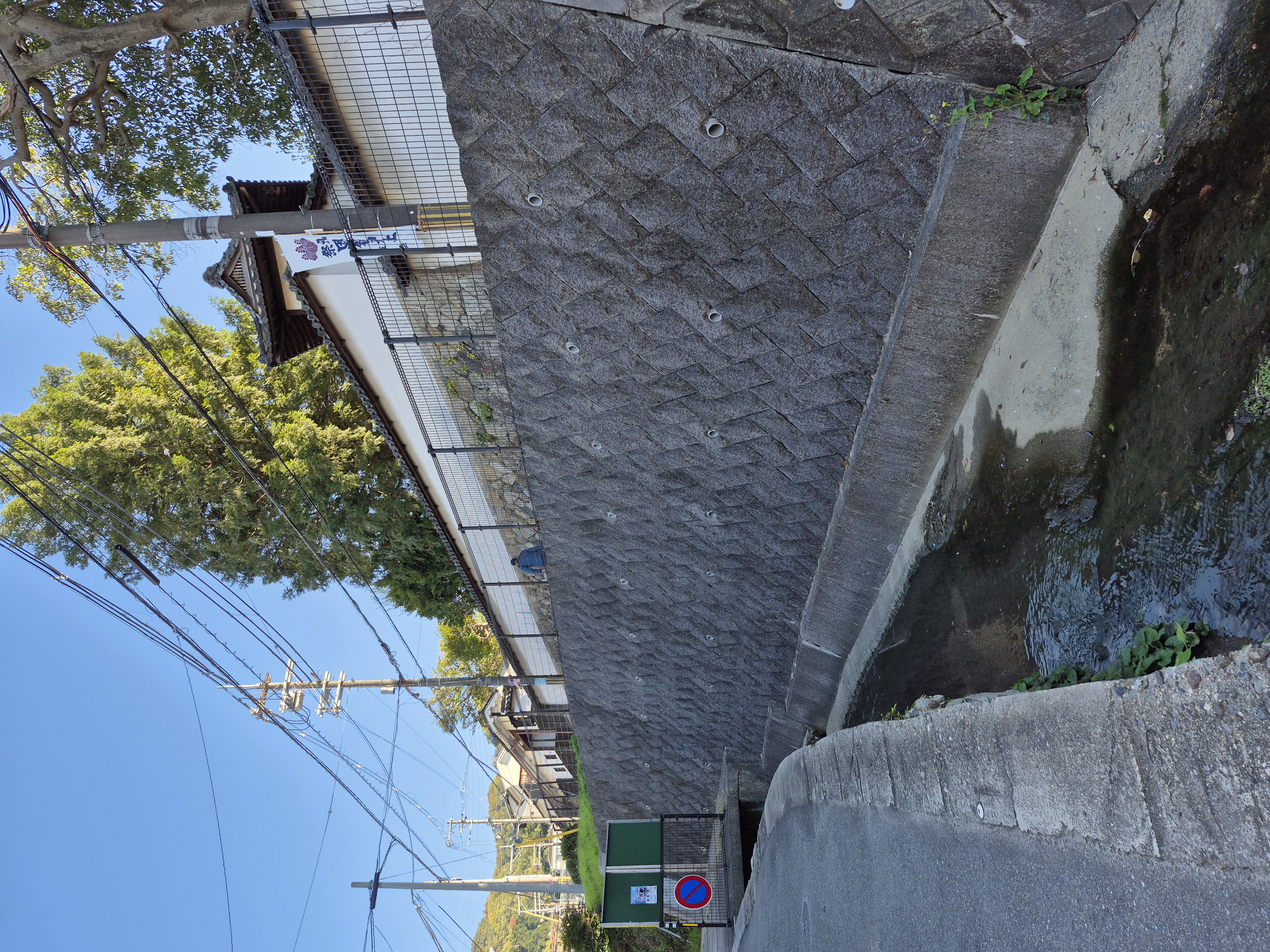 神社へ続く道と川の流れ、歴史を感じる屋敷の画像